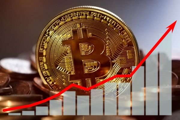 A gold Bitcoin (BTC) stands out against other coins with a rising bar graph. Buy crypto on Coinmama.